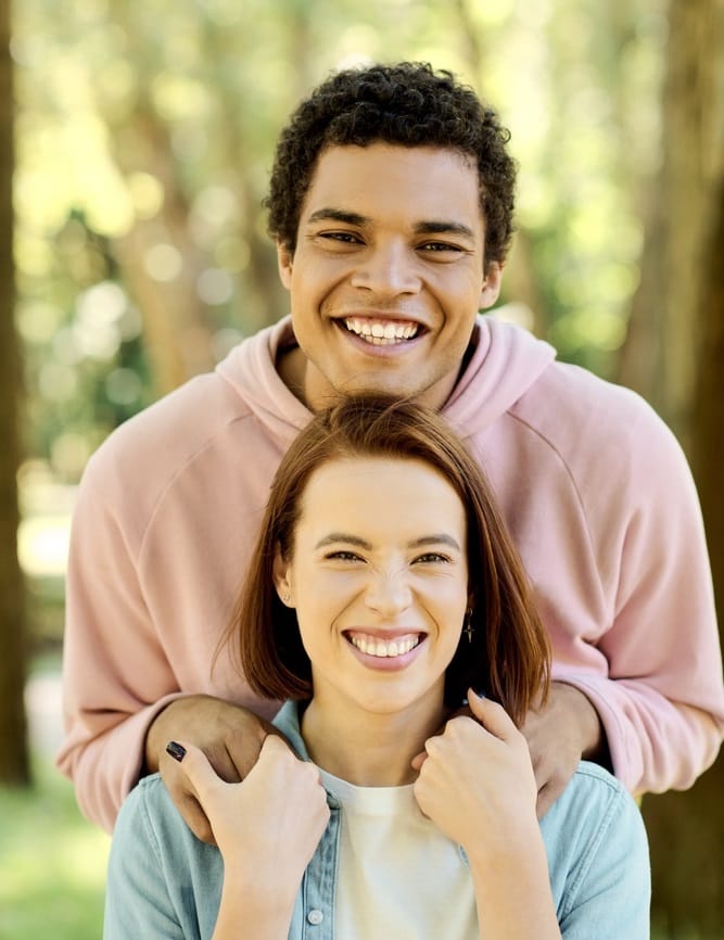 A young couple with beautiful teeth smiling by the water