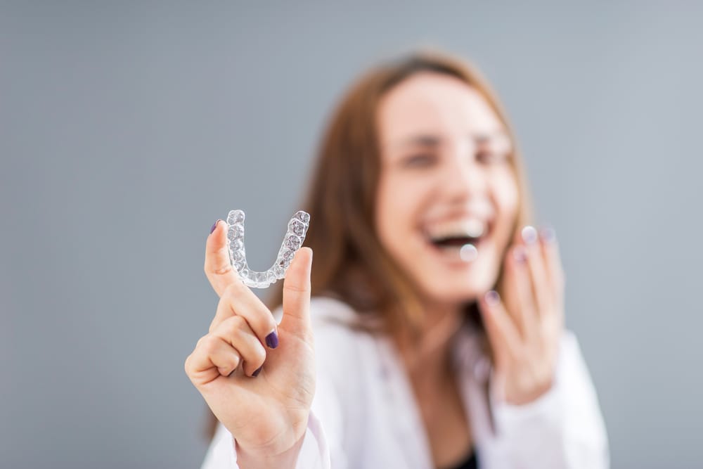 Beautiful smiling Turkish woman is holding an invisalign - Invisalign in Bellevue