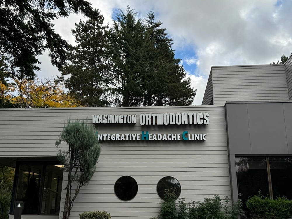 The exterior of "Washington Orthodontics & Integrative Headache Clinic" with surrounding trees and a partly cloudy sky - Washington Orthodontics The exterior of "Washington Orthodontics & Integrative Headache Clinic" with surrounding trees and a partly cloudy sky - Washington Orthodontics